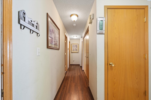 hallway with a textured ceiling and dark wood-type flooring