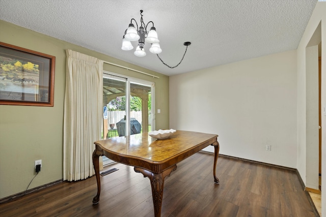 dining room featuring wood finished floors, a textured ceiling, baseboards, and a notable chandelier