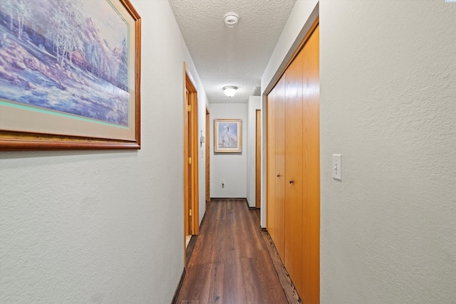 corridor featuring dark wood-type flooring and a textured ceiling