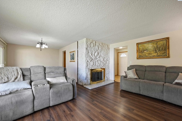 living area featuring a chandelier, a textured ceiling, dark wood-style floors, and a fireplace