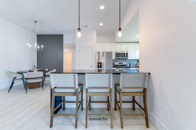6905 Rd 108, Pasco, WA 99301 - kitchen with appliances with stainless steel finishes, dark countertops, a chandelier, white cabinets, and tasteful backsplash