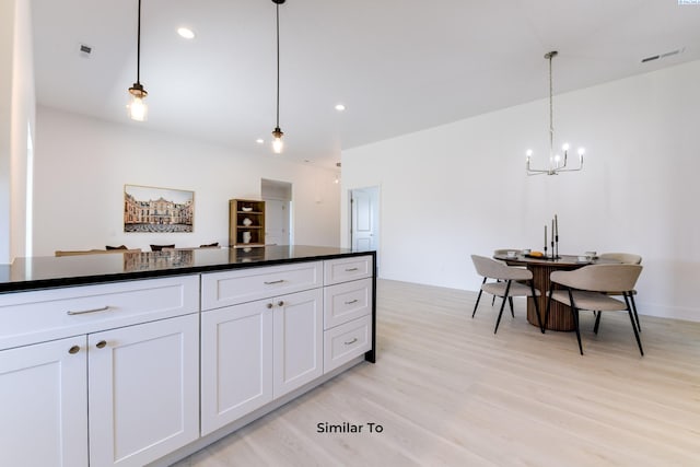 6905 Rd 108, Pasco, WA 99301 - kitchen with a chandelier, light wood finished floors, white cabinets, dark countertops, and pendant lighting
