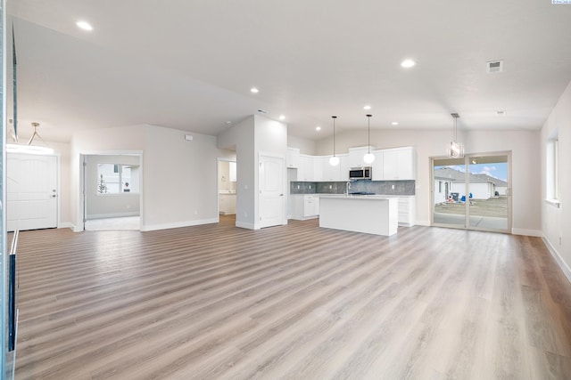10409 Kokanee Dr, Pasco, WA 99301 - unfurnished living room featuring vaulted ceiling, light wood finished floors, and recessed lighting