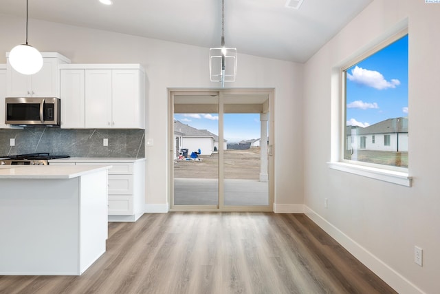 10409 Kokanee Dr, Pasco, WA 99301 - kitchen featuring stainless steel microwave, vaulted ceiling, backsplash, light wood finished floors, and light countertops