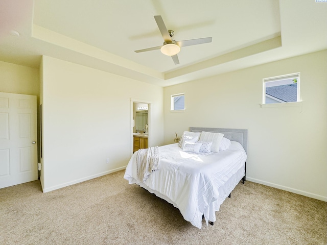 carpeted bedroom with baseboards, multiple windows, and a tray ceiling