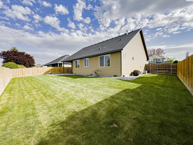rear view of property featuring a shingled roof, a lawn, a fenced backyard, and crawl space
