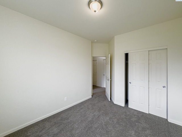 unfurnished bedroom featuring dark carpet, a closet, and baseboards