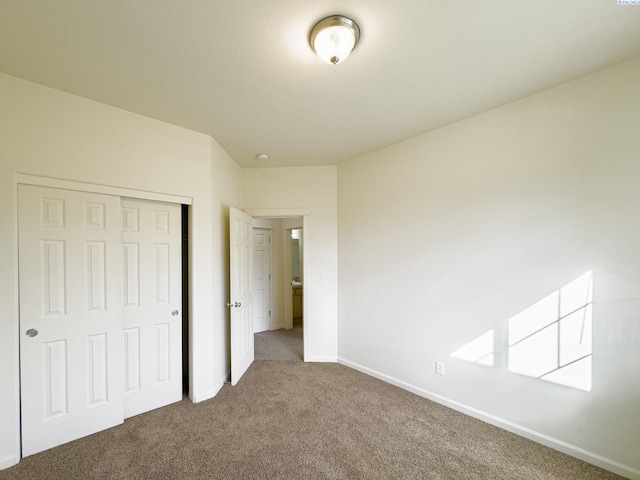 unfurnished bedroom featuring baseboards, carpet flooring, and a closet