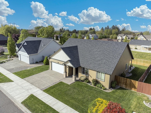 view of front of property featuring roof with shingles, a front lawn, concrete driveway, and fence