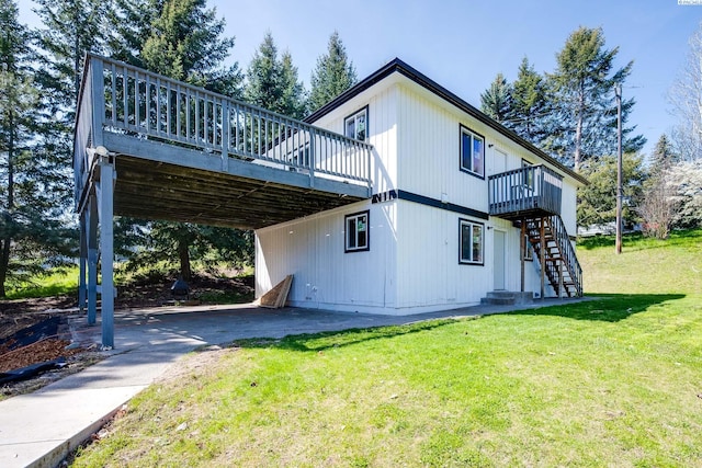 back of house featuring a lawn, a carport, a deck, and stairway