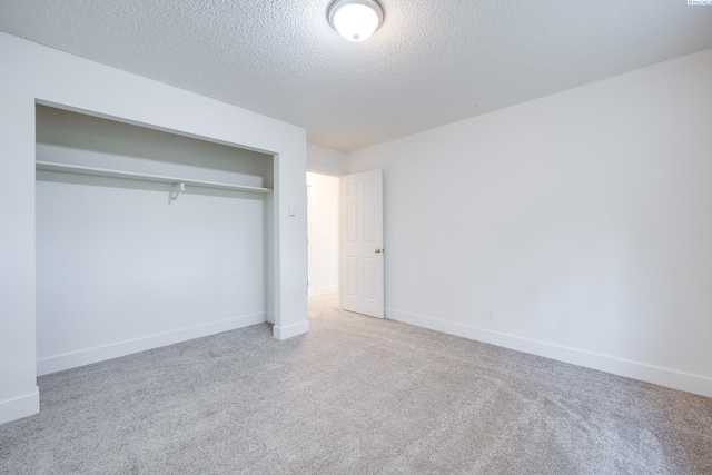 unfurnished bedroom featuring carpet floors, baseboards, a closet, and a textured ceiling