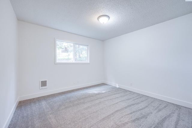 carpeted empty room featuring baseboards, a textured ceiling, and visible vents