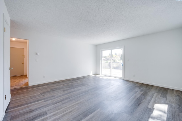 spare room with baseboards, a textured ceiling, and wood finished floors