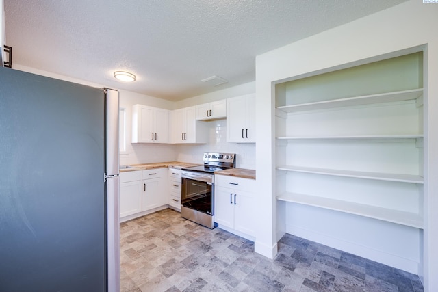 kitchen featuring white cabinets, open shelves, appliances with stainless steel finishes, a textured ceiling, and tasteful backsplash