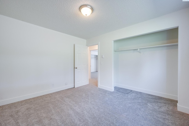 unfurnished bedroom featuring carpet floors, a textured ceiling, baseboards, and a closet