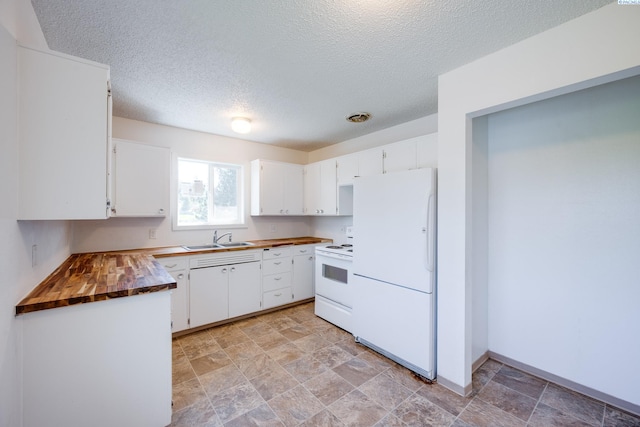 kitchen with white appliances, a textured ceiling, white cabinetry, a sink, and wood counters