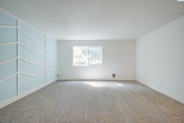 carpeted spare room featuring baseboards, a textured ceiling, and visible vents