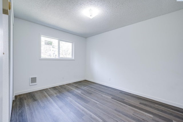 unfurnished room with visible vents, a textured ceiling, dark wood-style flooring, and baseboards