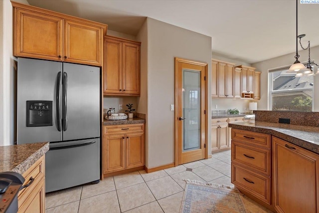 100 S Nevada St, Kennewick, WA 99336 - kitchen featuring stainless steel fridge, dark countertops, hanging light fixtures, light tile patterned floors, and brown cabinets