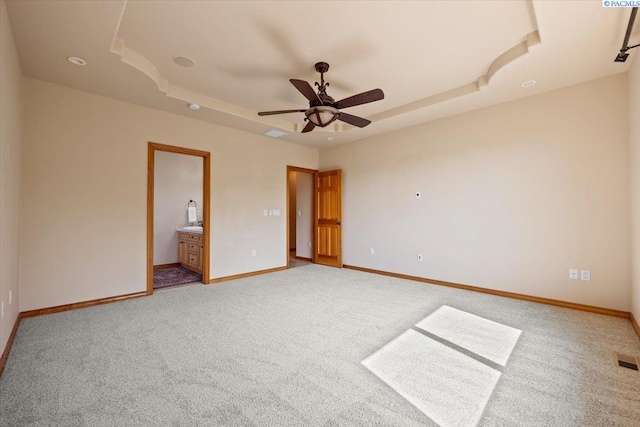 100 S Nevada St, Kennewick, WA 99336 - unfurnished bedroom featuring a raised ceiling, light carpet, ensuite bathroom, and a ceiling fan