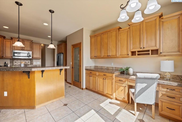 100 S Nevada St, Kennewick, WA 99336 - kitchen featuring stainless steel appliances, a breakfast bar, pendant lighting, brown cabinets, and light tile patterned floors