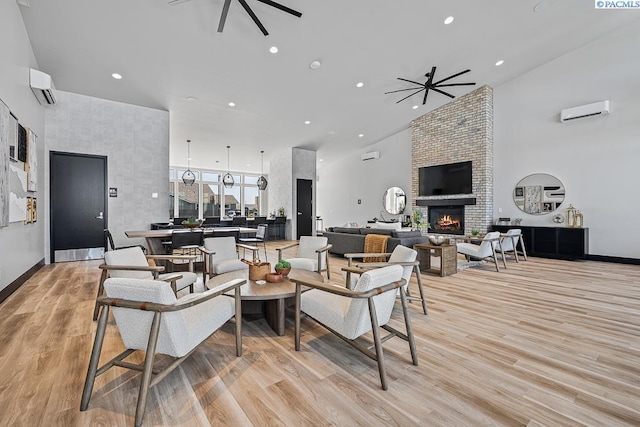 living room with a high ceiling, a wall mounted air conditioner, a fireplace, and ceiling fan