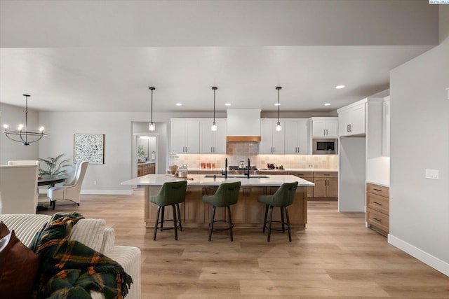 671 Cortona Way, Richland, WA 99352 - kitchen with stainless steel microwave, tasteful backsplash, a breakfast bar, light countertops, and a chandelier