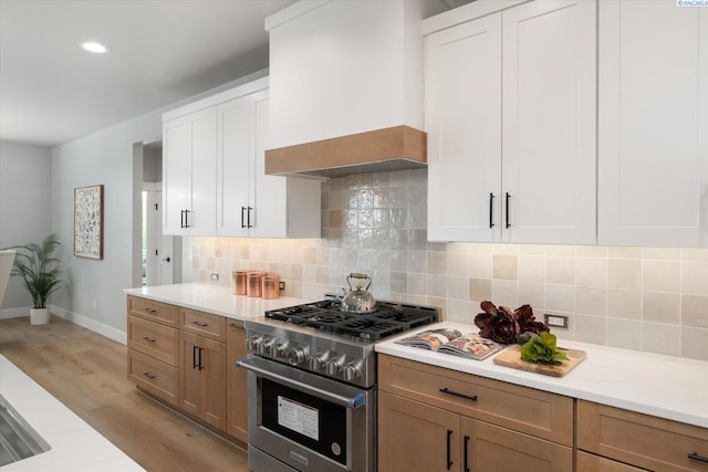 671 Cortona Way, Richland, WA 99352 - kitchen featuring high end stainless steel range, custom exhaust hood, light wood finished floors, backsplash, and white cabinets