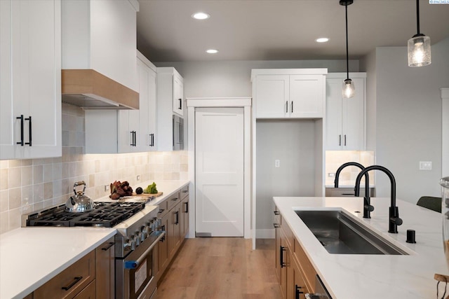 671 Cortona Way, Richland, WA 99352 - kitchen featuring high end stainless steel range oven, wall chimney range hood, light wood finished floors, pendant lighting, and tasteful backsplash