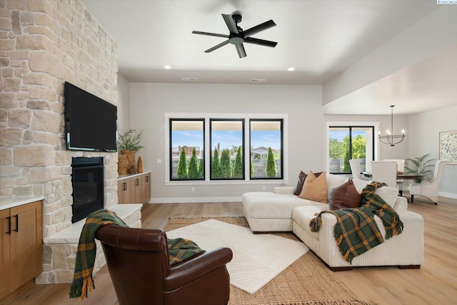 671 Cortona Way, Richland, WA 99352 - living area with a stone fireplace, a chandelier, light wood finished floors, a ceiling fan, and recessed lighting