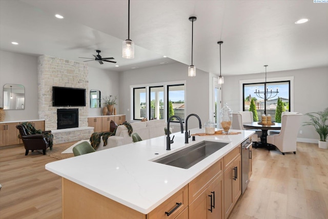 671 Cortona Way, Richland, WA 99352 - kitchen with light wood-style floors, plenty of natural light, recessed lighting, a stone fireplace, and an island with sink