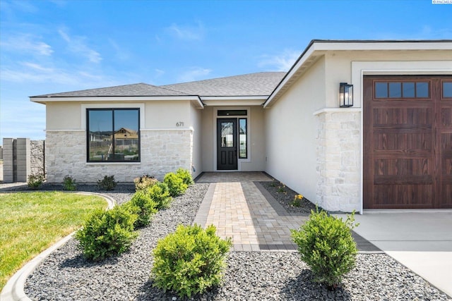 671 Cortona Way, Richland, WA 99352 - view of exterior entry featuring stone siding, stucco siding, a garage, a shingled roof, and driveway