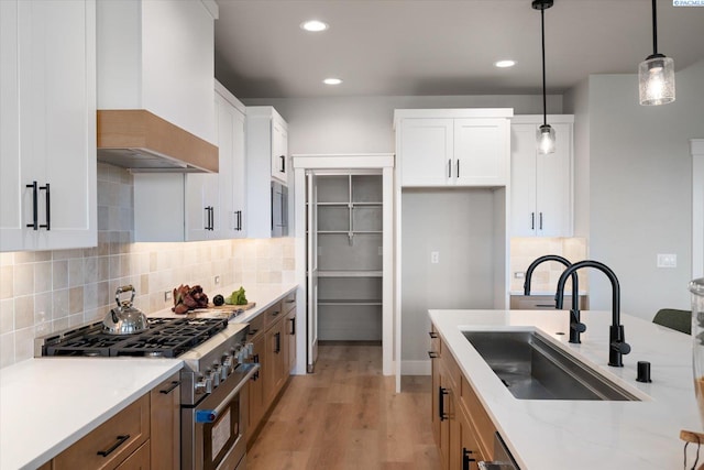 671 Cortona Way, Richland, WA 99352 - kitchen with stainless steel range, wall chimney exhaust hood, light wood-type flooring, decorative light fixtures, and tasteful backsplash