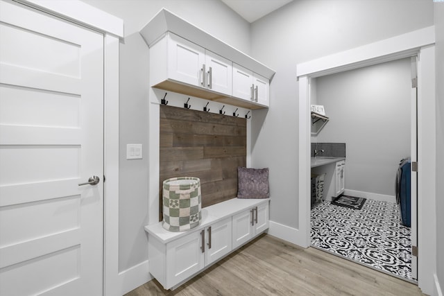 mudroom featuring light wood finished floors, a sink, and baseboards