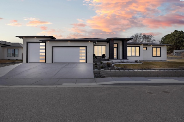 view of front of house featuring a garage, concrete driveway, and stucco siding