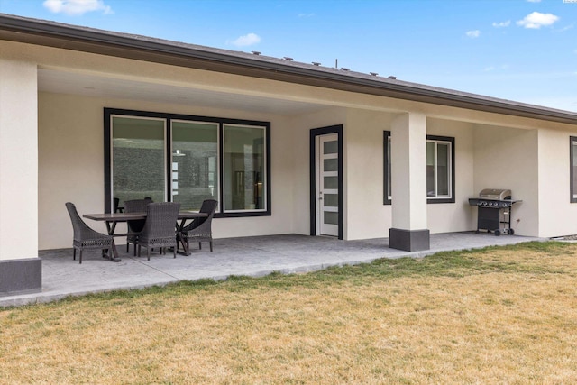 back of property with a yard, stucco siding, and a patio