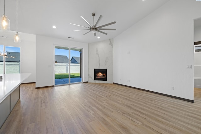 unfurnished living room with a premium fireplace, ceiling fan, and light hardwood / wood-style flooring