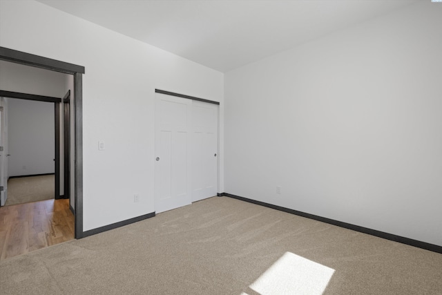 unfurnished bedroom with light colored carpet and a closet