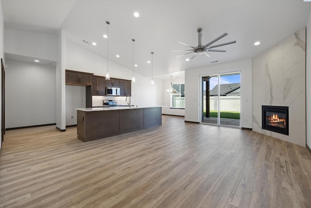 kitchen featuring pendant lighting, sink, a kitchen island with sink, a high end fireplace, and stainless steel appliances