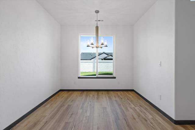 unfurnished dining area featuring light hardwood / wood-style floors and a chandelier