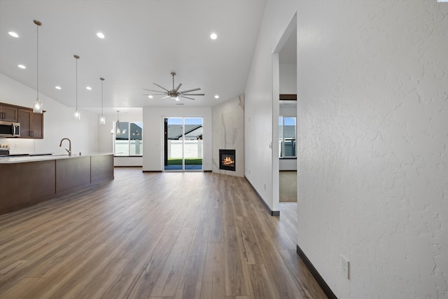 unfurnished living room with ceiling fan, dark hardwood / wood-style floors, sink, and a fireplace