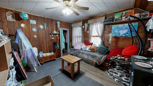 interior space featuring wood walls, ceiling fan, and wood finished floors