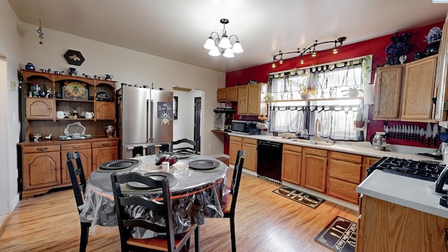 kitchen with stainless steel appliances, light countertops, light wood-style floors, a sink, and a chandelier