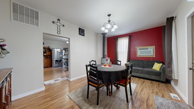 420 E Houghton St, Palouse, WA 99161 - dining area with a wood stove, light wood-style floors, baseboards, an AC wall unit, and a chandelier
