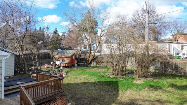 view of yard with a storage shed, a fenced backyard, a deck, and an outdoor structure