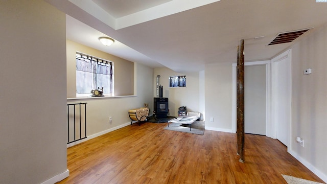 workout area with a wood stove, wood finished floors, visible vents, and baseboards