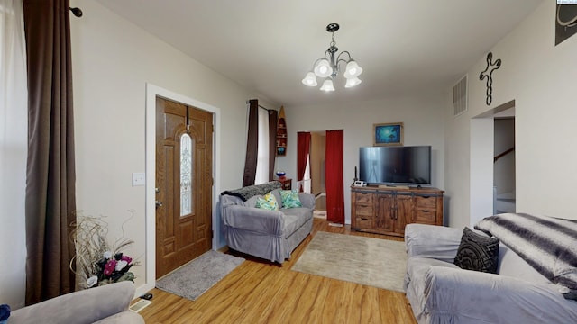 living room with visible vents, light wood finished floors, and an inviting chandelier