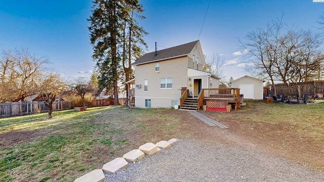 back of house featuring an outbuilding, a fenced backyard, a lawn, and a wooden deck