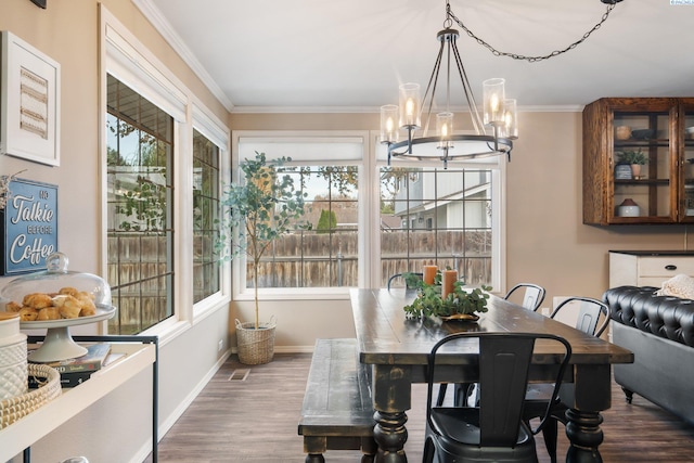dining room featuring a chandelier, wood finished floors, crown molding, and baseboards