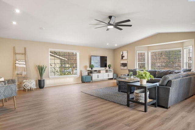 living area with plenty of natural light, vaulted ceiling, a ceiling fan, and light wood-type flooring